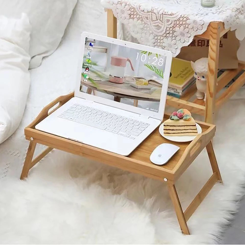 bamboo bed tray table holding a laptop, mouse, and snack beside a bed