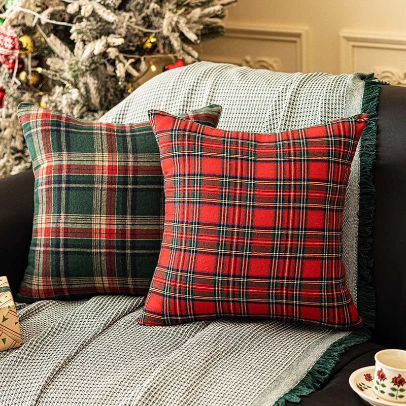 Close-up of green and red tartan plaid pillow covers on a sofa next to a Christmas tree