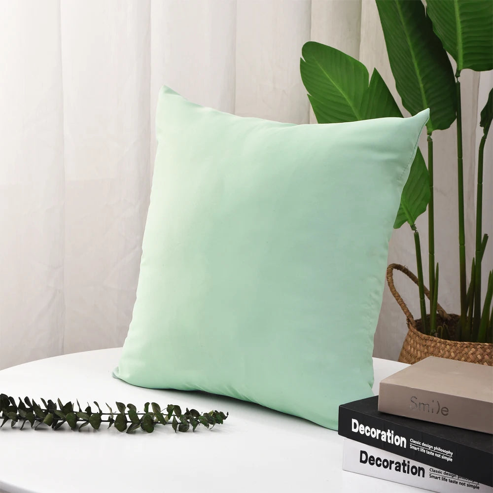 Light green square cushion cover displayed on a round table in a cozy room