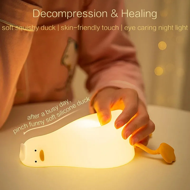 Hand squishing soft silicone duck night light on table, showing tactile flexibility