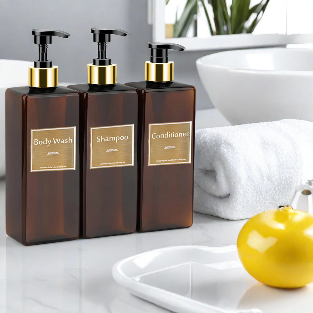 Brown rectangular soap dispenser bottles labeled for body wash, shampoo, and conditioner on a bathroom counter