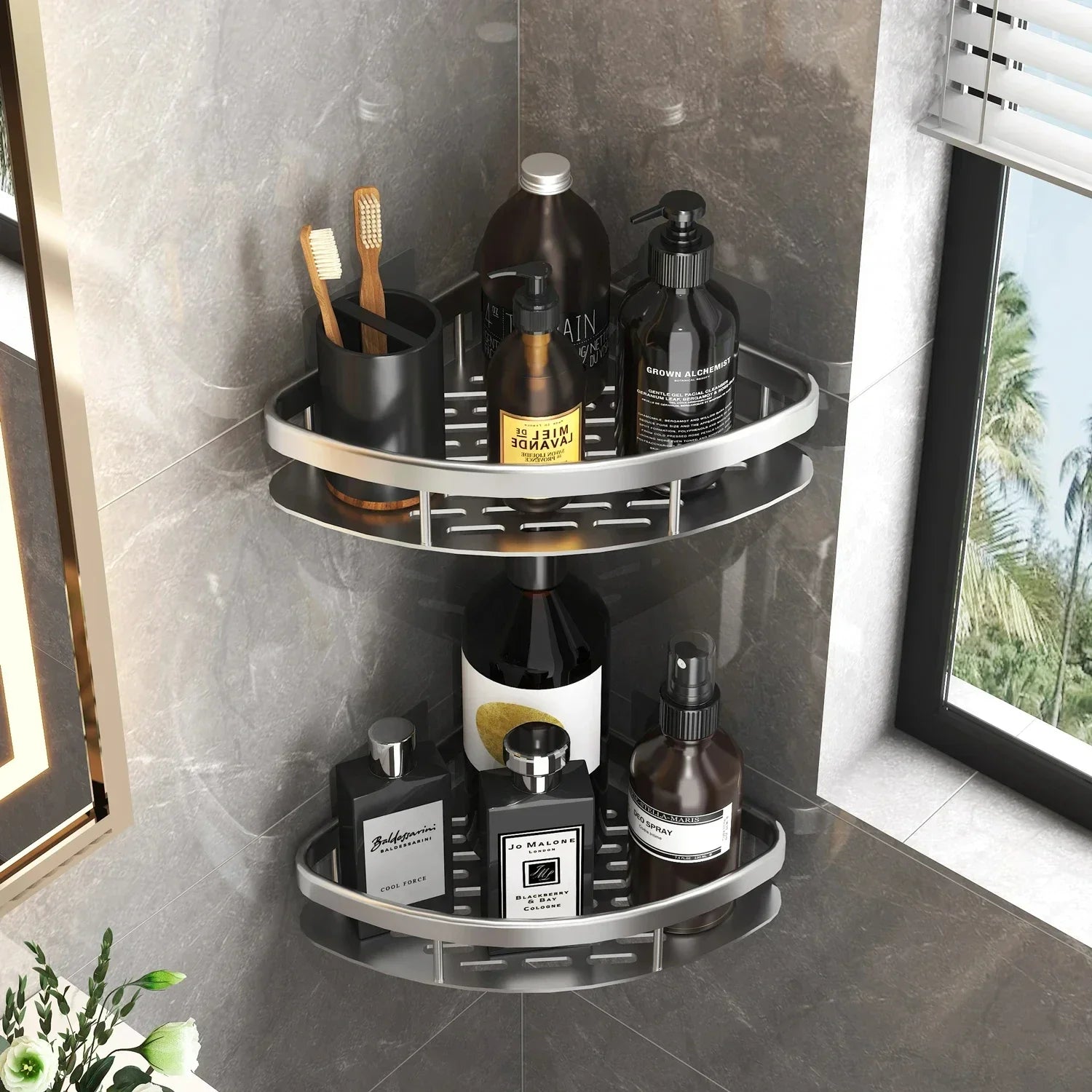 Silvery corner wall-mounted bathroom organizer shelves holding bottles and toothbrushes by a window.