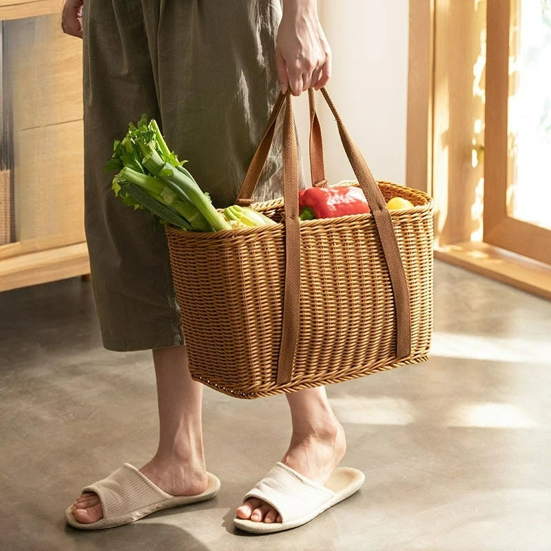 Person holding rattan storage basket tote with groceries in a sunlit kitchen